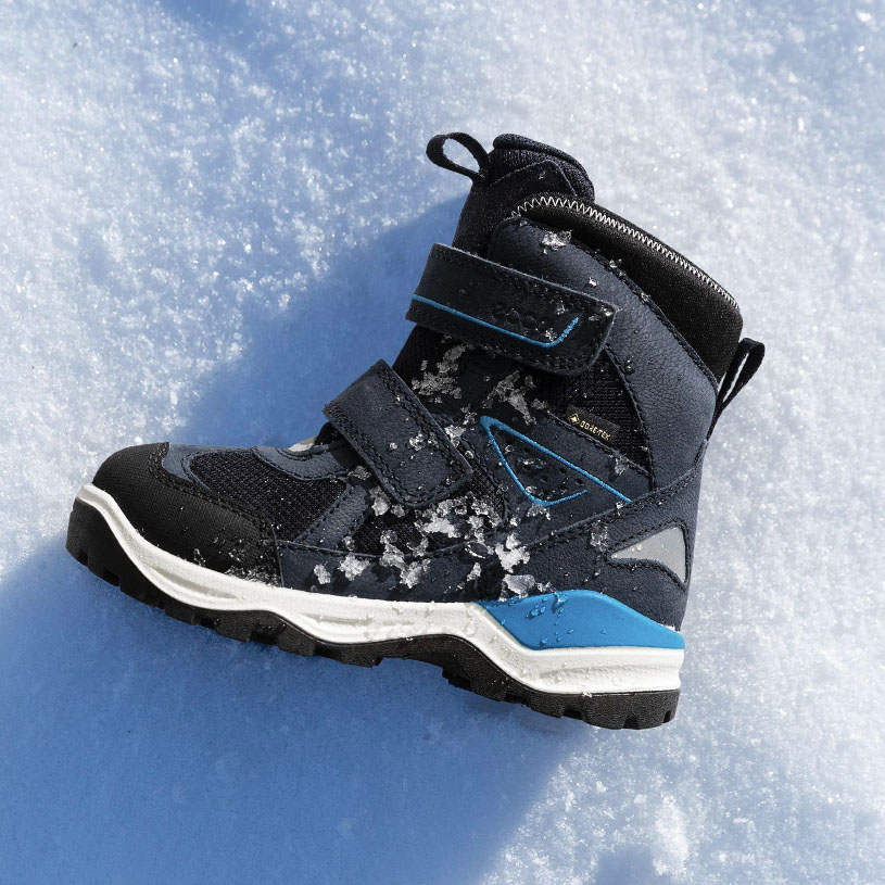 Talvikenkä lumessa, tummansininen tarrakiinnitys.