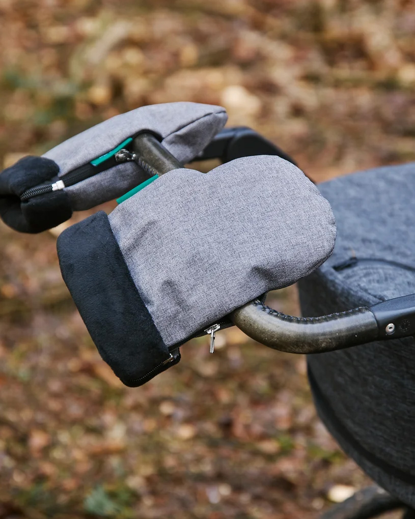 Käsineisiin puetut kädet tarttuvat vaunujen kahvaan laiturilla.