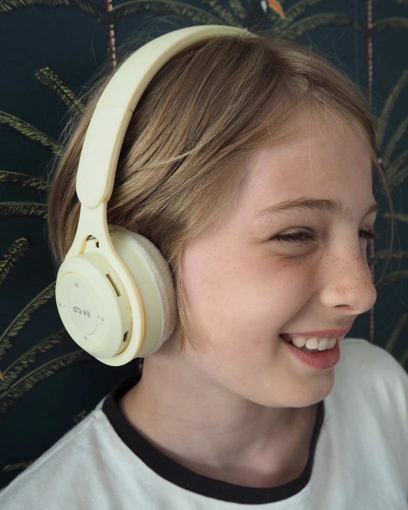 Vaaleahiuksinen lapsi käyttää isoja kuulokkeita ja hymyilee.