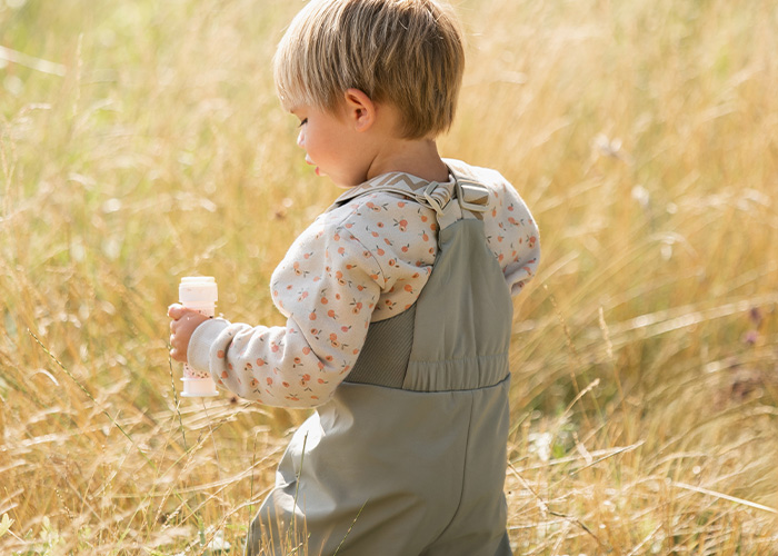 Lapsi harmaissa haalareissa pitää pulloa, tekstinä 'Kenza X Viking'.