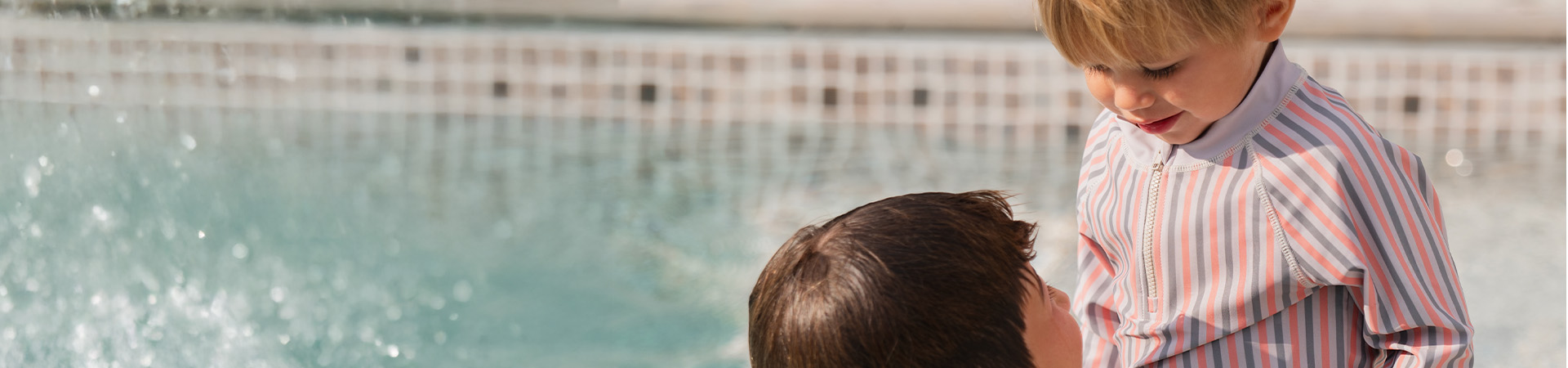 Äiti hymyilee lapselleen, joka pitää kukkaa, tekstillä 'Kenza X Viking'.