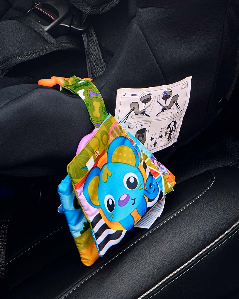 Värikäs lelu turvaistuimessa käyttöohjeella.