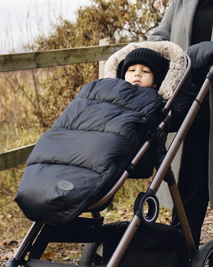 Lapsi rattaissa mustassa makuupussissa kävelyllä.