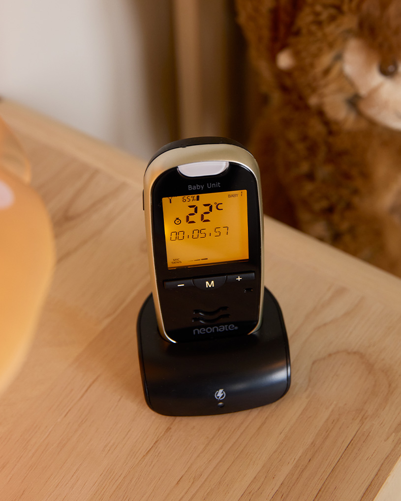 Nukkuva vauva pinnasängyssä, vauvanvahti yöpöydällä.