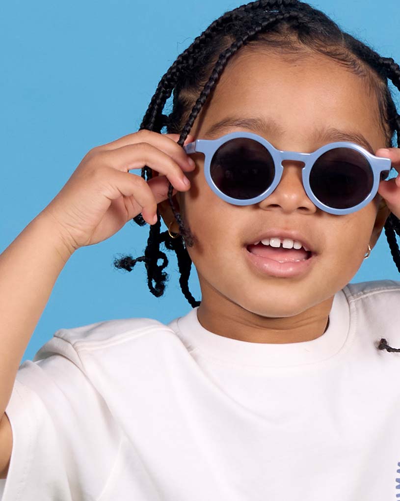 Lapsi aurinkolaseilla oljilla, vihreä teksti: 'Uutuus!'