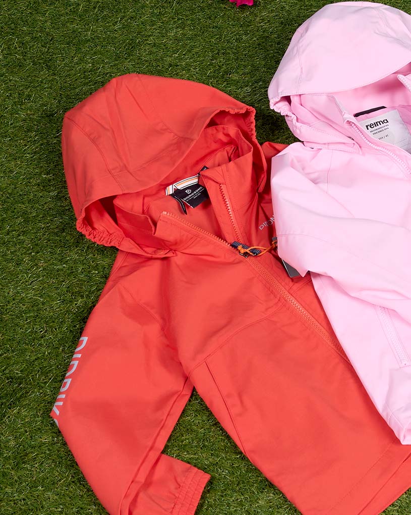 Lapsi, jolla pitkät hiukset ja lippis, beige Didriksons-takki ulkona.