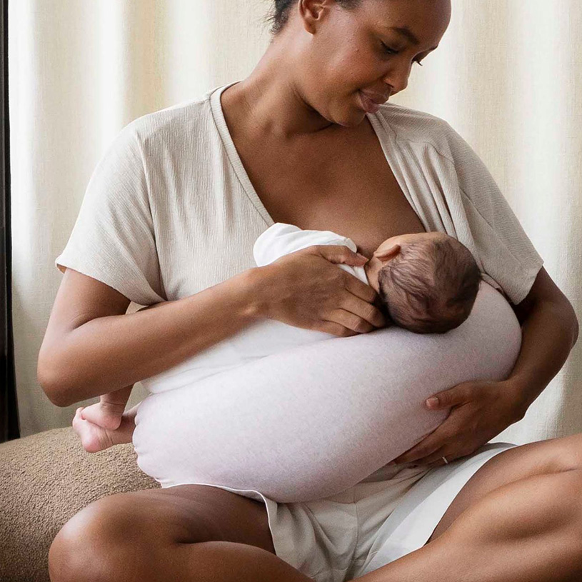 Nainen imettää vauvaa tyynyn päällä.