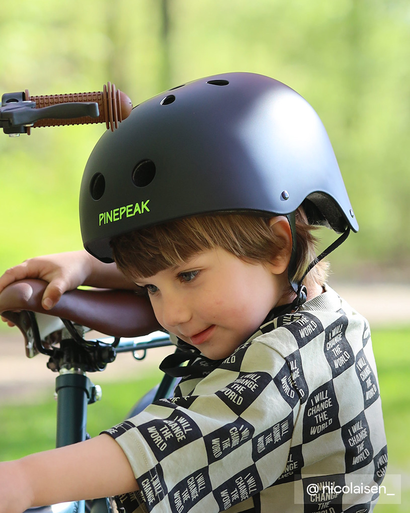 Lapsi kypärällä pyörällä, paita tekstillä 'I will change the world'.