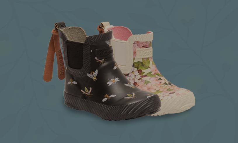 Kaksi lasten saapasta: musta mehiläiskuvioilla, valkoinen kukkakuviolla.